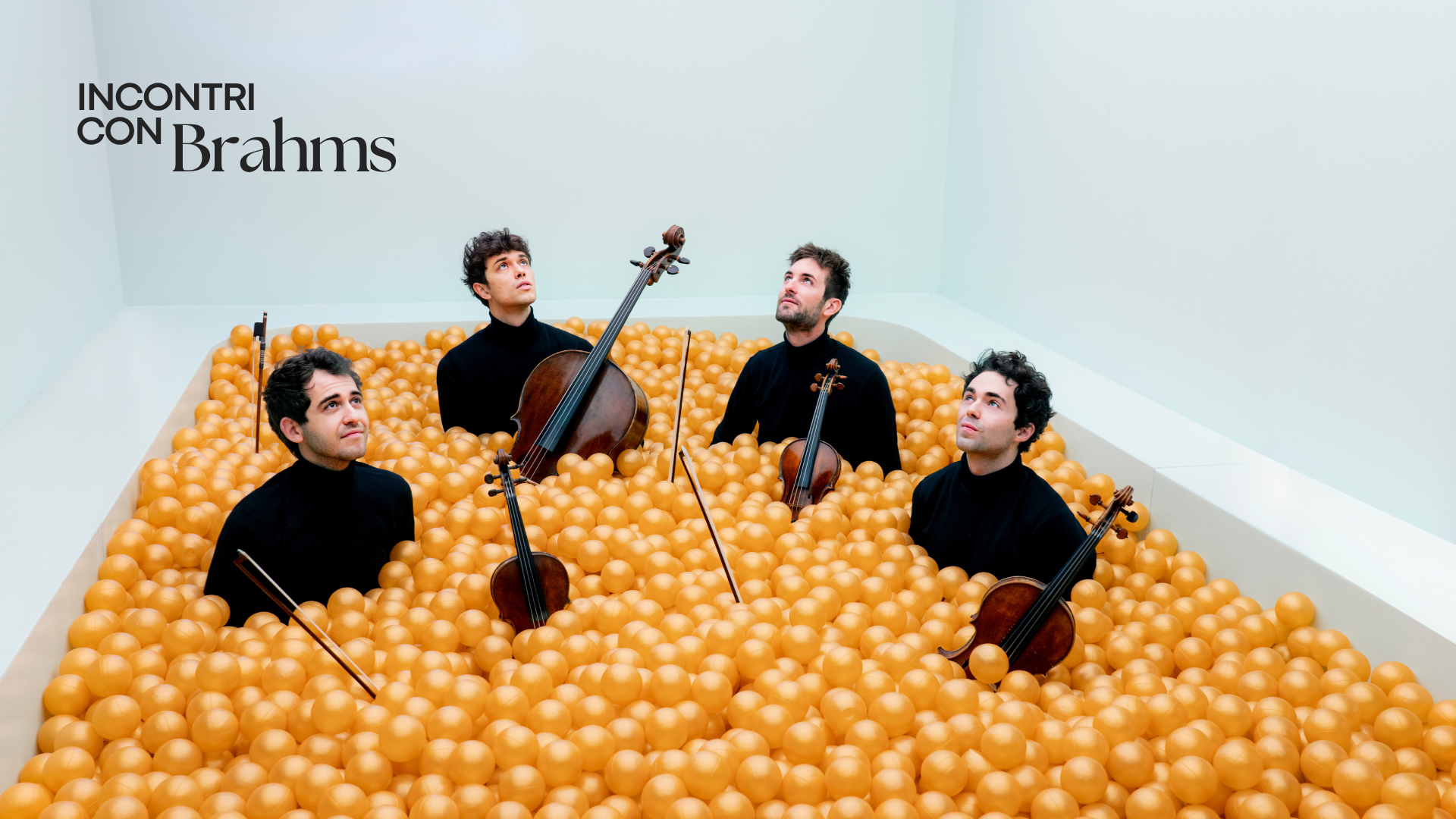 foto dei componenti del Vision String Quartet con i loro strumenti in una vasca piena di palline di color arancio